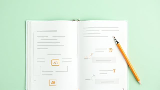 Isang open textbook na may stylus at diagram ng curriculum, nagpapakita ng proseso ng pagbuo ng edukasyon.